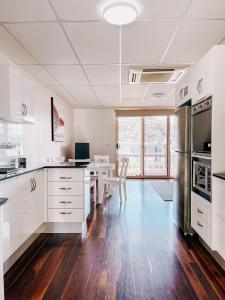 una cocina con armarios blancos y una mesa y sillas blancas. en Riverfront Dream on the Hawkesbury - Water View, en Brooklyn