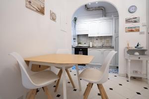 a kitchen with a wooden table and white chairs at appartamento fronte mare con terrazzo in Alassio