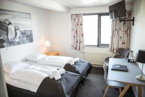 Duas camas num quarto com uma mesa e uma secretária. em Hotel Runavík em Runevig