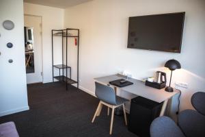 ein Zimmer mit einem Schreibtisch und einem Fernseher an der Wand in der Unterkunft Hotel Runavík in Runevig