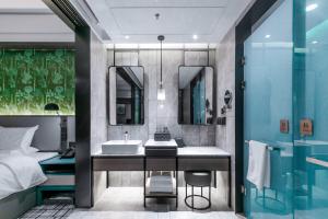 a bathroom with a sink and a bed and a mirror at Qingdao Treasure Hotel in Qingdao