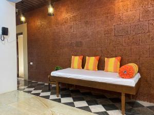 una panca con cuscini colorati su un muro di mattoni di Ola Agro Riverside Villa in Malvan, Dhamapur, Sindhudurg a Pendur