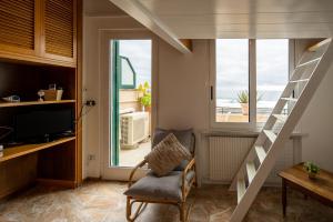 sala de estar con escalera, silla y ventana en Appartamento fronte mare con terrazzo zio, en Alassio