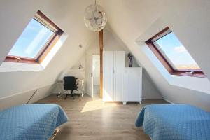a attic bedroom with two beds and two windows at Gemütliche 2 Zimmerwohnung mit TV und WLAN in Wendlingen am Neckar