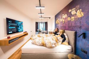 two women laying in bed in a room with a tv at Hofgasse Apartments in Innsbruck