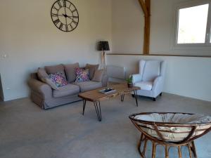a living room with a couch and a table and a clock at l'airial in Souprosse