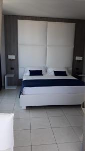 a bedroom with a white bed with a large headboard at Hotel Cristallo in Riccione