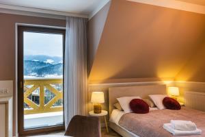 ein Schlafzimmer mit einem Bett und einem großen Fenster in der Unterkunft Przystanek Babia Apartamenty in Lipnica Wielka + 37 Fotos