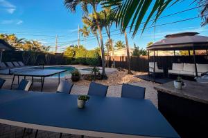 a blue table and chairs in a backyard with palm trees at 5BR! Pool, Air Hockey, Playground, Gazebo, BBQ, Sleeps 16 in Miami