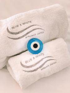 een witte handdoek met een blauwe knop erop bij Blue, White and Grey Suites in Ornos