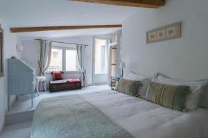 ein weißes Schlafzimmer mit einem großen Bett und einem Fenster in der Unterkunft La Marisol in LʼIsle-sur-la-Sorgue