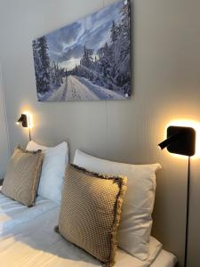 a bedroom with a bed with two pillows and a painting on the wall at Vikingskipet Hotell in Hamar