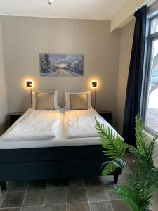 a bedroom with a bed with two lamps and a plant at Vikingskipet Hotell in Hamar