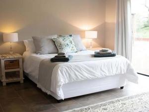 1 dormitorio con cama blanca y ventana en East of East Guest Cottage, en Avondzon