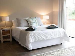 a bedroom with a white bed and a window at East of East Guest Cottage in Avondzon