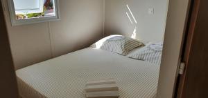 een klein bed in een kleine kamer met een raam bij Mobilhome chez Cathy & Simon in Marseillan