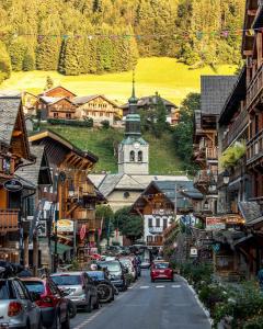 une ville avec des voitures garées dans une rue avec une église dans l'établissement La Grangette - Morzine, à Morzine