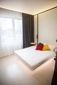 1 dormitorio con 1 cama blanca grande con almohadas coloridas en Sunday Rooms en Odesa