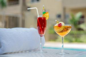 two cocktails sitting on a table next to a pool at Rosewood by Amaryllis Lilongwe in Lilongwe
