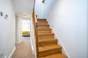 - un escalier dans une maison dotée de murs blancs et de parquet dans l'établissement JOIVY Modern 4 bed flat with communal courtyard in Angel, East London, à Londres
