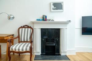 - un salon avec une cheminée noire et une chaise dans l'établissement JOIVY Modern 4 bed flat with communal courtyard in Angel, East London, à Londres