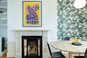 a fireplace in a dining room with a table and a painting at ALTIDO Modern 4 bed flat with communal courtyard in Angel, East London in London