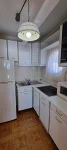 ベニドルムにあるLas Damasの白いキャビネット、シンク、照明付きのキッチンが備わります。