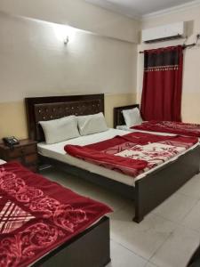 1 dormitorio con 2 camas con sábanas rojas y cortina en Hotel Khursheed Palace, en Rawalpindi