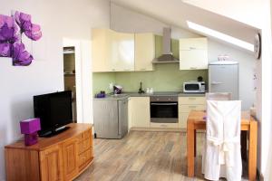 a kitchen with white cabinets and a table with a television at Apartment LuVi in Korčula