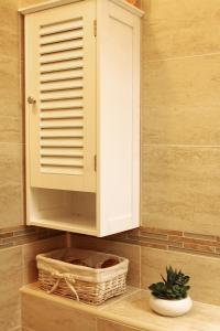 a cabinet in a bathroom with a basket and a plant at Apartment LuVi in Korčula