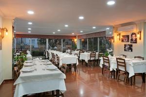 アンタルヤにあるララ ディンチ ホテルのテーブルと椅子(白いテーブルクロス付)が備わるレストラン