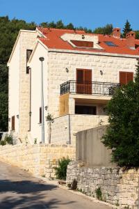 a large white house with a stone wall at Apartment LuVi in Korčula