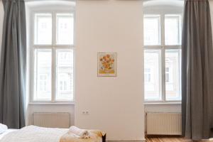 a bedroom with white walls and windows and a bed at Pleasant 3BR City Stay near Event Location Wiener Stadthalle in Vienna