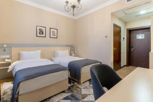 a hotel room with two beds and a chair at Navruz Hotel Tashkent in Tashkent