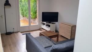 een woonkamer met een bank en een flatscreen-tv bij FleuryTerre - Grand 2 pièces avec terrasse in Déville-lès-Rouen