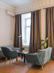 a living room with two chairs and a table and a window at Caps Hotel на Остоженке in Moscow