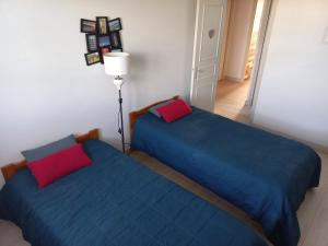 two beds in a room with blue and red pillows at Location 44410 in Saint-Lyphard