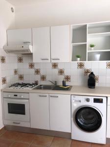 a kitchen with white cabinets and a washing machine at BERNARDINI Emplacement exceptionnel in Sari Solenzara