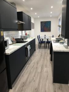 a kitchen with black cabinets and a table with chairs at Stylish modern 3-bed house nr Manchester city ctr in Whitefield