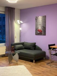 1 Room, near to UN und Telekom في بون: غرفة معيشة مع أريكة خضراء وجدار أرجواني