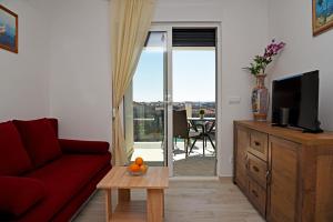 uma sala de estar com um sofá vermelho e uma televisão em Apartman Barbara em Trogir
