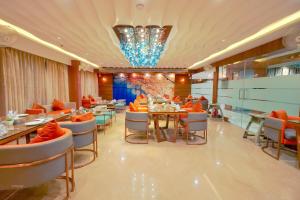 a restaurant with tables and chairs and a chandelier at RG Exclusive Hotel- Akola in Akola