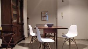 a dining room with a wooden table and white chairs at Piccinni house in Bari