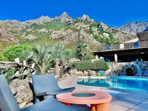 a house with a swimming pool with a mountain at Hôtel Domaine A Flatta in Calenzana