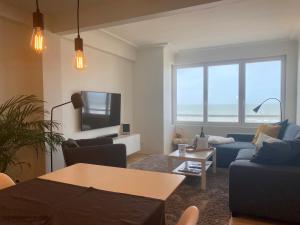 a living room with a blue couch and a tv at OSKAR luxe appartement op zeedijk met zeezicht in Ostend