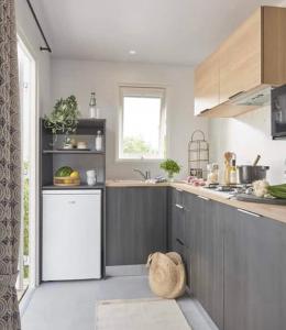 uma cozinha com armários cinzentos e um frigorífico branco em Prachtig nieuw chalet met tuin op De Friese Wadden em Tzummarum