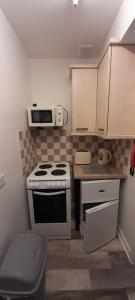 a small kitchen with a stove and a microwave at Cosy Mews House Close to Harbour in Porthmadog