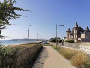 a path next to a beach with a building at Le petit logis de Barneville plage in Barneville-Carteret