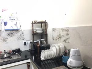 a kitchen with a counter top with white dishes at shavāsanā homestay in Vānivilāsa Puram