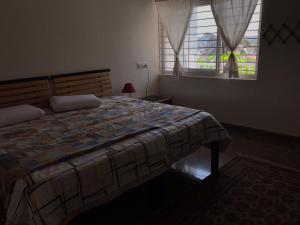 a bedroom with a large bed and a window at shavāsanā homestay in Vānivilāsa Puram